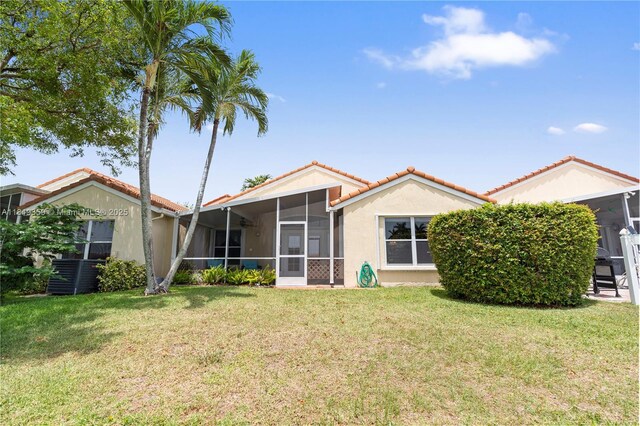7182 Burgess Dr, Lake Worth, FL 33467 - back of house featuring a sunroom, a tiled roof, stucco siding, a yard, and central AC unit