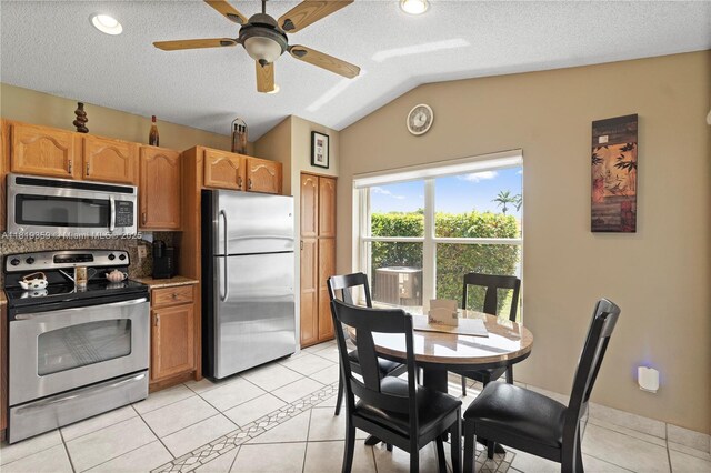 7182 Burgess Dr, Lake Worth, FL 33467 - kitchen with stainless steel appliances, vaulted ceiling, a textured ceiling, light tile patterned flooring, and a ceiling fan