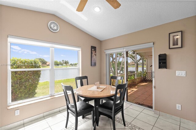 7182 Burgess Dr, Lake Worth, FL 33467 - dining space featuring a water view, vaulted ceiling, ceiling fan, light tile patterned floors, and a textured ceiling