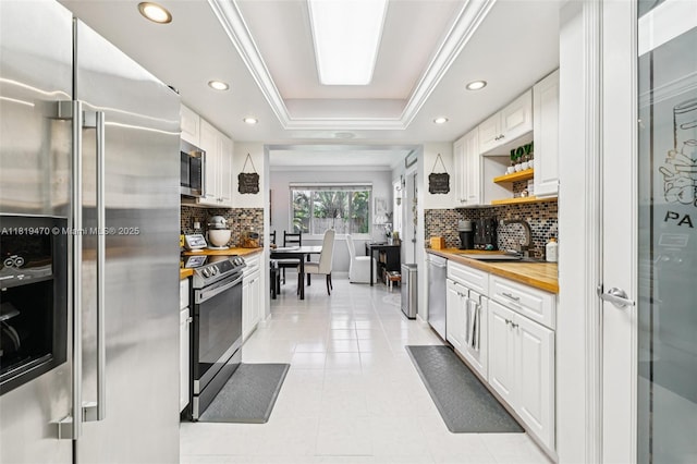 2375 NW 81st Ave, Sunrise, FL 33322 - kitchen with stainless steel appliances, wood counters, white cabinetry, tasteful backsplash, and a raised ceiling