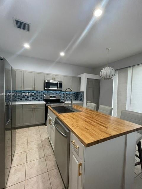 18796 SW 27th Ct, Miramar, FL 33029 - kitchen with appliances with stainless steel finishes, butcher block countertops, a kitchen island with sink, backsplash, and recessed lighting