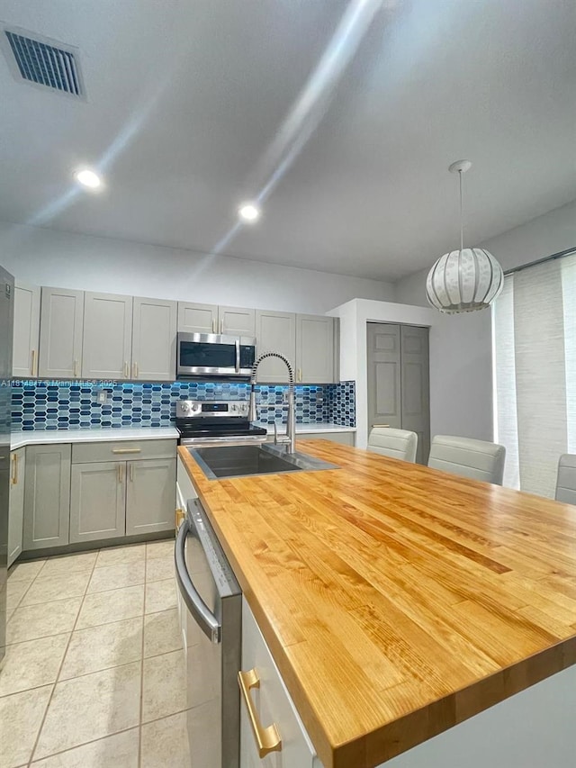 18796 SW 27th Ct, Miramar, FL 33029 - kitchen featuring wood counters, stainless steel appliances, a sink, backsplash, and a center island with sink