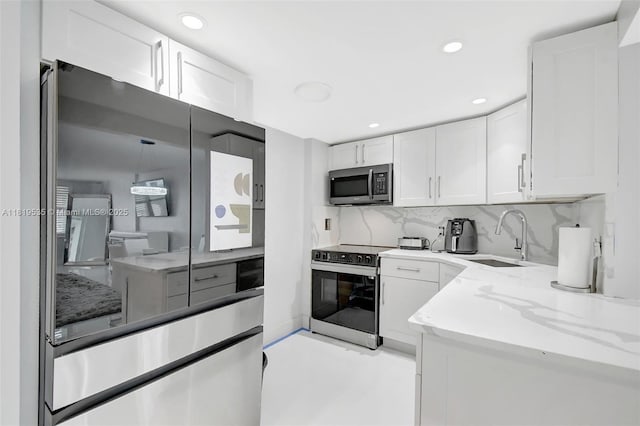 3015 N Ocean Blvd Unit 4K, Fort Lauderdale, FL 33308 - kitchen with appliances with stainless steel finishes, a sink, white cabinets, decorative backsplash, and light stone countertops