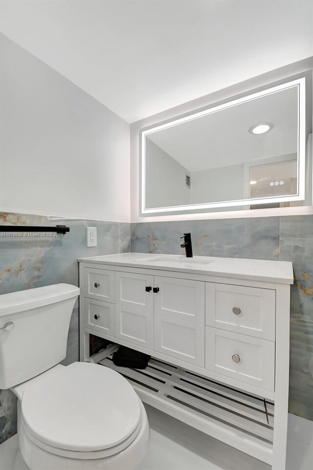 3015 N Ocean Blvd Unit 4K, Fort Lauderdale, FL 33308 - bathroom with tile walls, toilet, vanity, and wainscoting