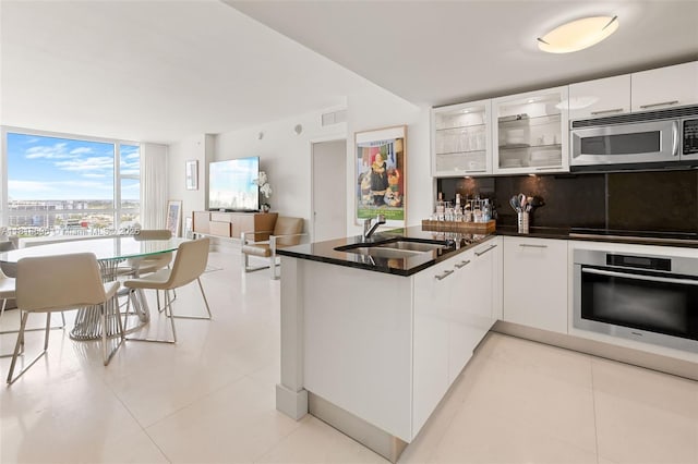 6801 Collins Ave Unit 1401, Door Number Miami Beach, FL 33141 - kitchen featuring stainless steel appliances, a sink, a peninsula, tasteful backsplash, and white cabinets