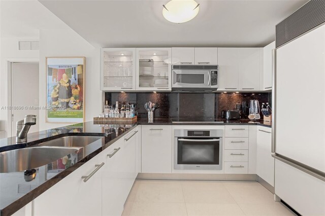 6801 Collins Ave Unit 1401, Door Number Miami Beach, FL 33141 - kitchen featuring stainless steel appliances, a sink, decorative backsplash, white cabinets, and dark stone countertops