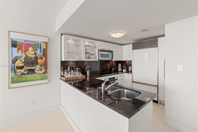 6801 Collins Ave Unit 1401, Door Number Miami Beach, FL 33141 - kitchen with stainless steel microwave, built in refrigerator, a sink, white cabinetry, and a peninsula