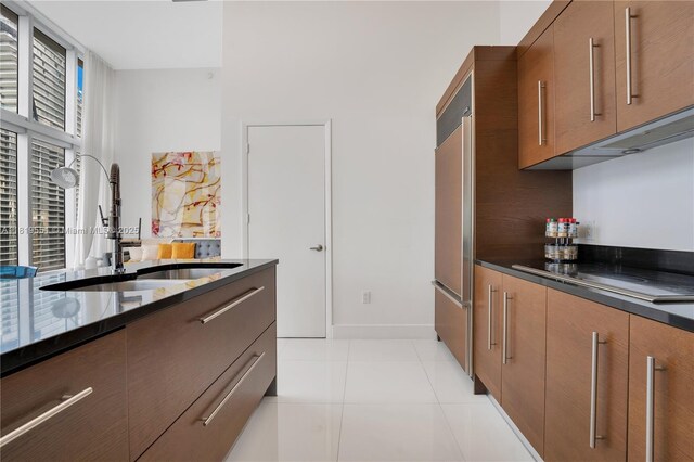485 Brickell Ave Unit 4004, Miami, FL 33131 - kitchen with black electric cooktop, brown cabinets, light tile patterned flooring, modern cabinets, and dark stone countertops