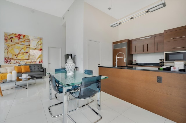 485 Brickell Ave Unit 4004, Miami, FL 33131 - kitchen with a high ceiling, black microwave, light tile patterned floors, dark countertops, and high end refrigerator