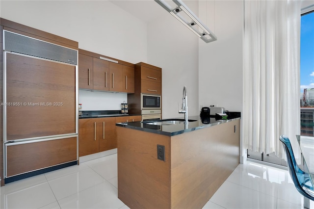 485 Brickell Ave Unit 4004, Miami, FL 33131 - kitchen featuring built in appliances, light tile patterned floors, brown cabinetry, a high ceiling, and a peninsula