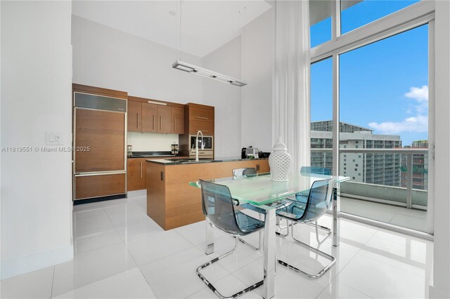 485 Brickell Ave Unit 4004, Miami, FL 33131 - kitchen featuring brown cabinetry, paneled built in fridge, a towering ceiling, a peninsula, and dark countertops