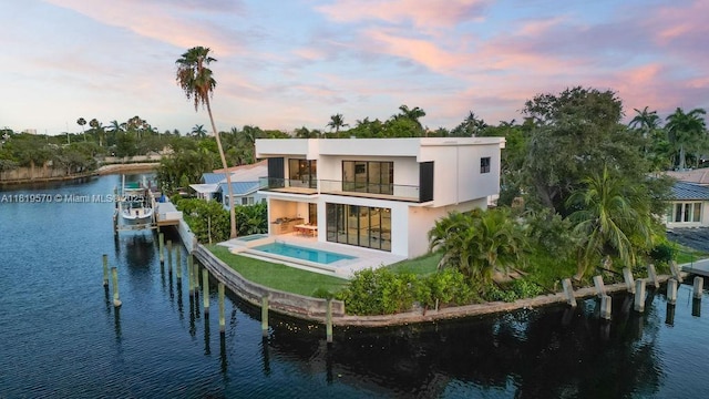 2033 NE 22nd St, Wilton Manors, FL 33305 - rear view of property with a balcony, a water view, stucco siding, a pool with connected hot tub, and a patio area
