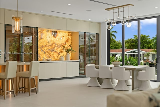 2033 NE 22nd St, Wilton Manors, FL 33305 - dining area with a chandelier, healthy amount of natural light, concrete floors, and a wall of windows