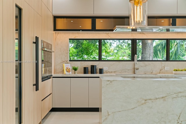 2033 NE 22nd St, Wilton Manors, FL 33305 - kitchen with range hood, light stone countertops, modern cabinets, and oven