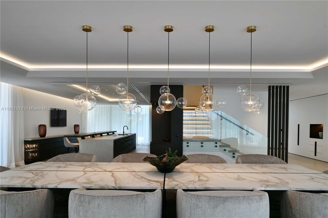375 N Hibiscus Dr, Miami Beach, FL 33139 - kitchen with a chandelier, a tray ceiling, pendant lighting, and an island with sink
