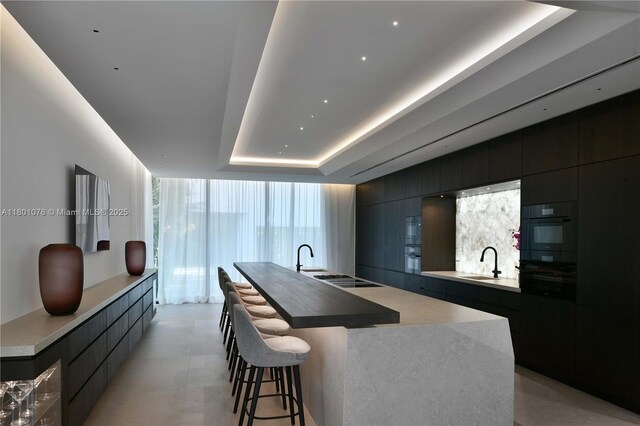 375 N Hibiscus Dr, Miami Beach, FL 33139 - kitchen featuring modern cabinets, a raised ceiling, a large island with sink, and a kitchen breakfast bar