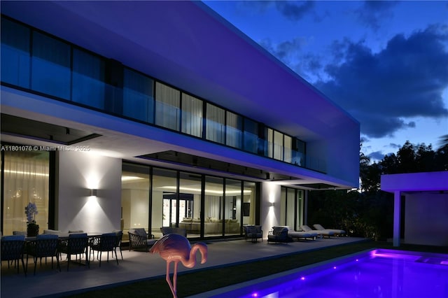 375 N Hibiscus Dr, Miami Beach, FL 33139 - back of house at night with a balcony, a patio, and an outdoor pool