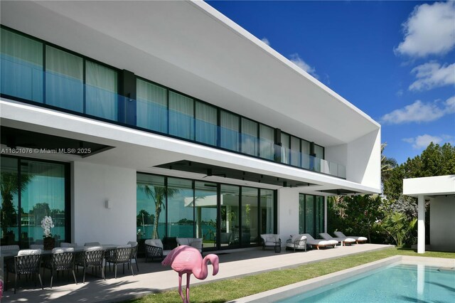 375 N Hibiscus Dr, Miami Beach, FL 33139 - back of house with a balcony, a patio, an outdoor pool, and stucco siding