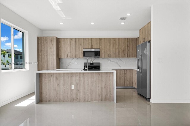 19446 SW 296th St Unit A, Homestead, FL 33030 - kitchen with stainless steel appliances, modern cabinets, light countertops, an island with sink, and brown cabinetry