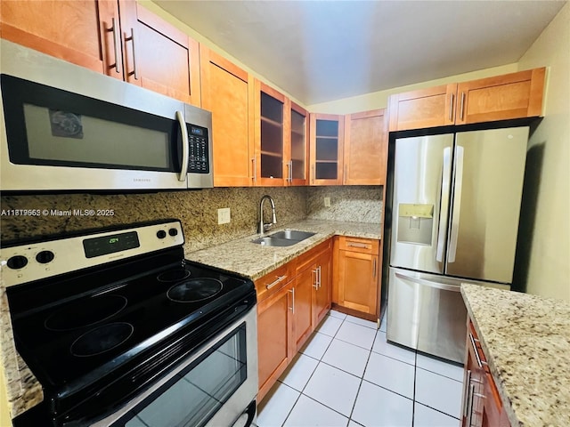 8511 NW 8th St Unit 103, Miami, FL 33126 - kitchen with stainless steel appliances, a sink, light stone countertops, light tile patterned flooring, and glass insert cabinets