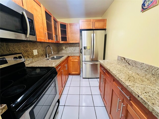 8511 NW 8th St Unit 103, Miami, FL 33126 - kitchen featuring appliances with stainless steel finishes, a sink, light stone countertops, tasteful backsplash, and glass insert cabinets