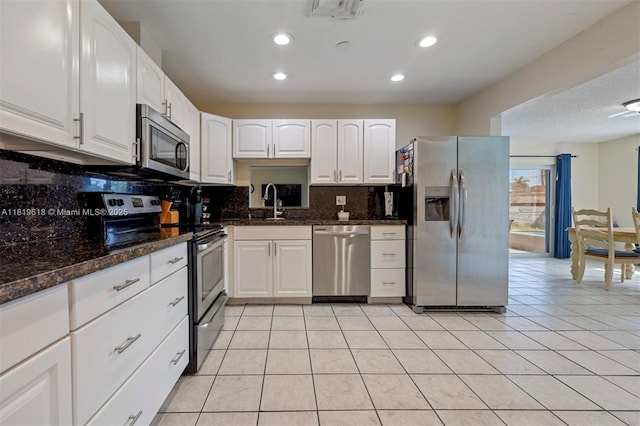 740 NW 97th Ter, Pembroke Pines, FL 33024 - kitchen with appliances with stainless steel finishes, white cabinetry, tasteful backsplash, light tile patterned floors, and dark stone counters