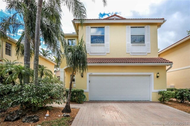 1120 Papaya St, Hollywood, FL 33019 - mediterranean / spanish-style house with stucco siding, an attached garage, a tile roof, and decorative driveway