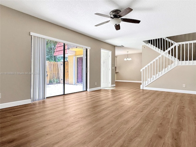 9920 NW 6th Pl Unit 9920, Plantation, FL 33324 - unfurnished living room with wood finished floors, ceiling fan, stairs, a chandelier, and a textured ceiling