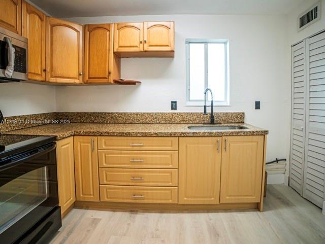 412 Columbus Pkwy, Hollywood, FL 33021 - kitchen featuring black range with electric stovetop, a sink, stainless steel microwave, light wood-style floors, and dark stone counters