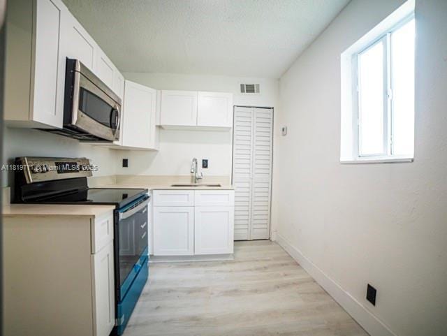 412 Columbus Pkwy, Hollywood, FL 33021 - kitchen with stainless steel appliances, a sink, white cabinets, light wood-style flooring, and light countertops
