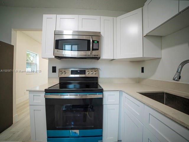 412 Columbus Pkwy, Hollywood, FL 33021 - kitchen with appliances with stainless steel finishes, a sink, light countertops, and white cabinets