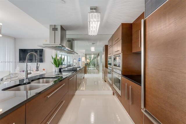 495 Brickell Ave Unit 3604, Miami, FL 33131 - kitchen with a sink, island range hood, brown cabinetry, and dark countertops
