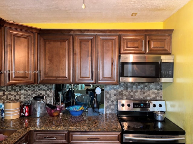 301 Cambridge Rd Unit 302, Hollywood, FL 33024 - kitchen with appliances with stainless steel finishes, a textured ceiling, tasteful backsplash, and dark stone counters
