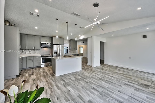 2273 SW Phyllis Ln, Port St Lucie, FL 34953 - kitchen with stainless steel appliances, gray cabinets, open floor plan, tasteful backsplash, and light countertops