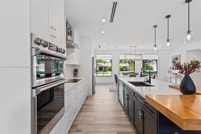 7570 SW 60th St, Miami, FL 33143 - kitchen featuring stainless steel appliances, a sink, white cabinetry, wood counters, and recessed lighting