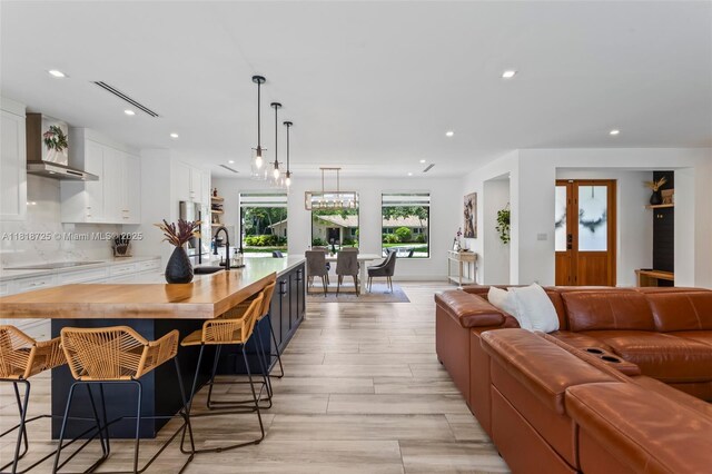 7570 SW 60th St, Miami, FL 33143 - kitchen featuring wall chimney exhaust hood, open floor plan, recessed lighting, white cabinets, and a sink