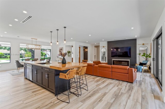 7570 SW 60th St, Miami, FL 33143 - kitchen featuring a sink, light wood-style floors, a kitchen island with sink, a breakfast bar area, and pendant lighting