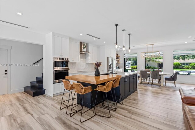 7570 SW 60th St, Miami, FL 33143 - kitchen with stainless steel double oven, wall chimney range hood, white cabinets, black electric stovetop, and recessed lighting