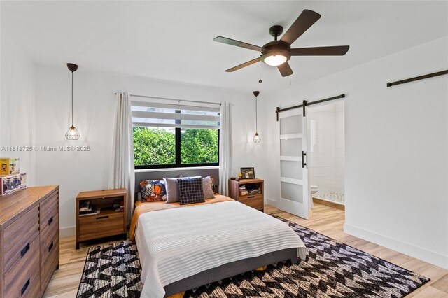 7570 SW 60th St, Miami, FL 33143 - bedroom featuring a barn door, light wood finished floors, and baseboards