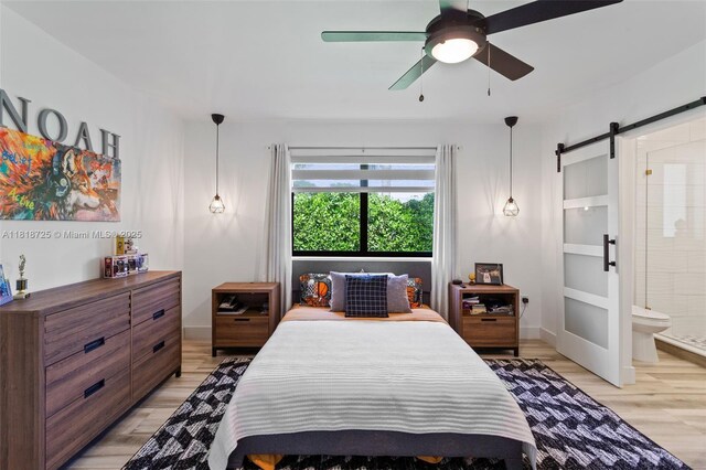 7570 SW 60th St, Miami, FL 33143 - bedroom featuring a barn door, light wood-style floors, ensuite bath, and a ceiling fan