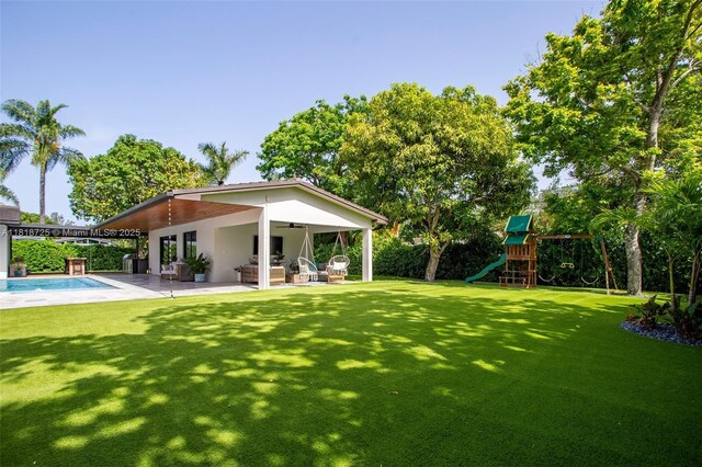 7570 SW 60th St, Miami, FL 33143 - view of green lawn featuring ceiling fan, a playground, and a patio area