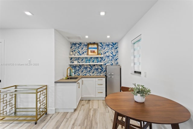 7570 SW 60th St, Miami, FL 33143 - kitchen with white cabinets, a sink, freestanding refrigerator, light wood-type flooring, and recessed lighting