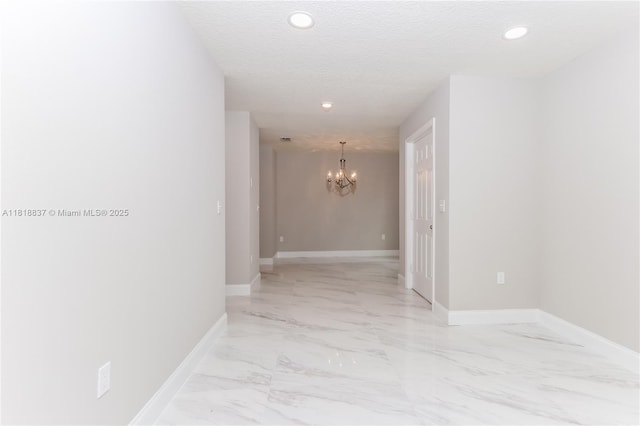 2635 SW Acco Rd, Port St Lucie, FL 34953 - hallway with a chandelier, recessed lighting, light marble finish flooring, and a textured ceiling