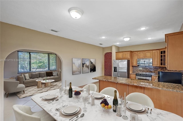 100 NW 23rd Ave, Miami, FL 33125 - kitchen with appliances with stainless steel finishes, a peninsula, a breakfast bar, brown cabinets, and recessed lighting