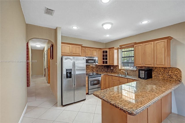 100 NW 23rd Ave, Miami, FL 33125 - kitchen featuring stainless steel appliances, arched walkways, a peninsula, backsplash, and glass insert cabinets