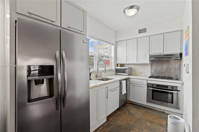 760 Meridian Ave Unit 3, Miami Beach, FL 33139 - kitchen with appliances with stainless steel finishes, a sink, under cabinet range hood, dark stone finish flooring, and white cabinets