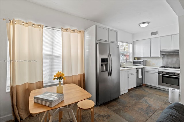 760 Meridian Ave Unit 3, Miami Beach, FL 33139 - kitchen with stainless steel appliances, dark stone finish floors, light countertops, under cabinet range hood, and a sink