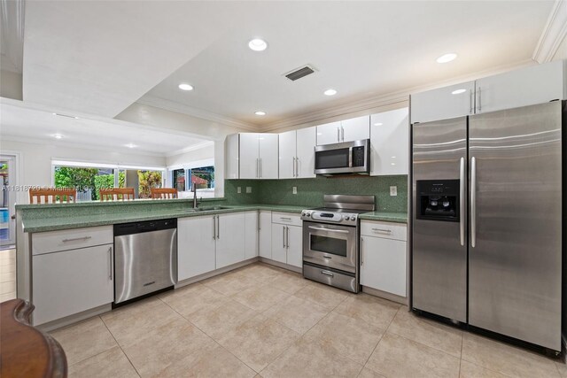 6231 SW 27th St, Miami, FL 33155 - kitchen featuring appliances with stainless steel finishes, ornamental molding, white cabinetry, tasteful backsplash, and a peninsula