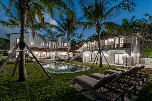 outdoor pool featuring french doors, a lawn, and a patio area
