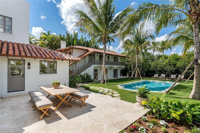 outdoor pool with outdoor dining space, a patio, a lawn, and stairs